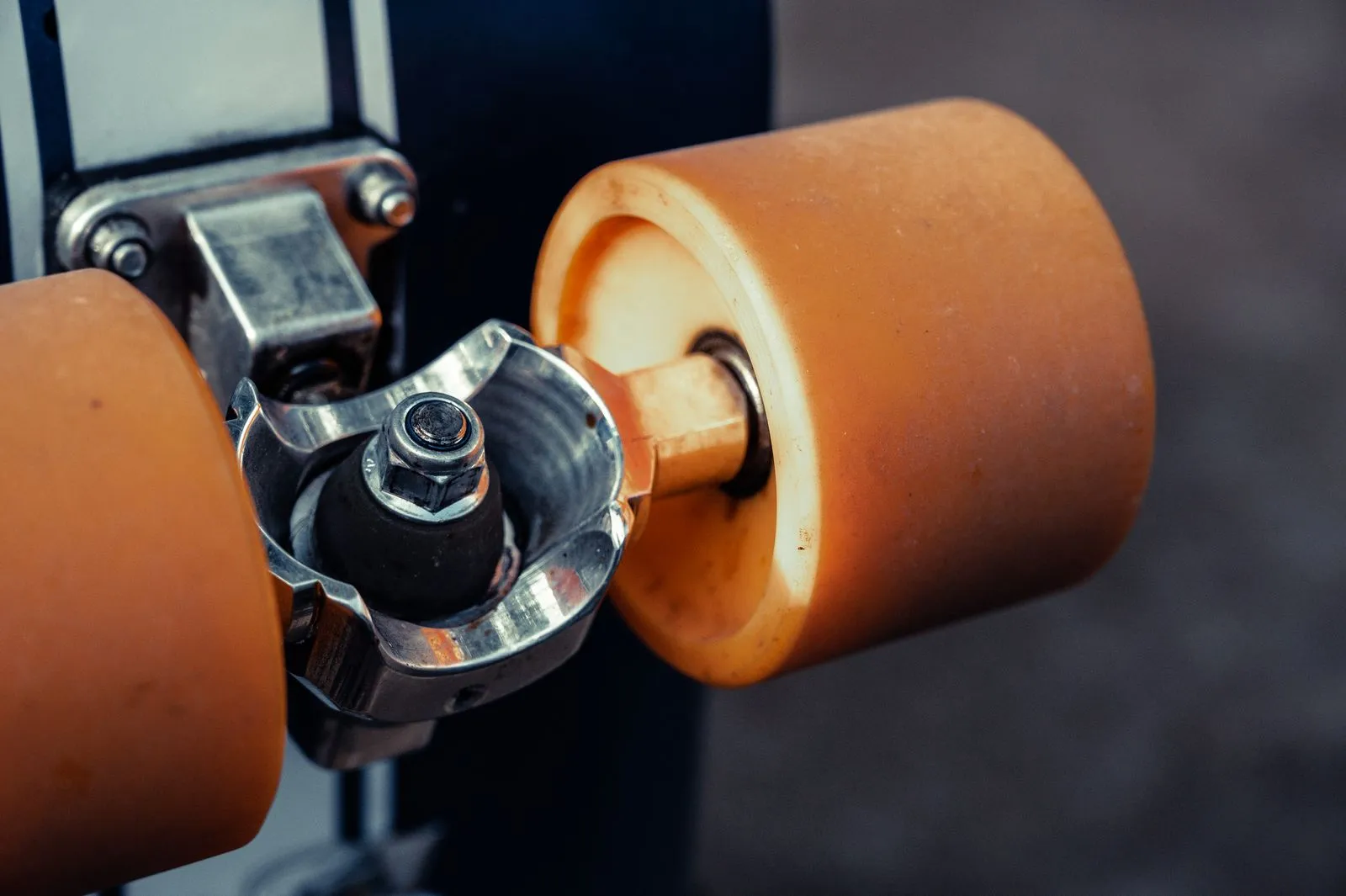 Detailed view of a skateboard's orange wheel and metal truck, highlighting components.